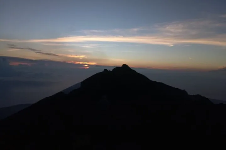 The dark silhouette of a mountain peak against a twilight sky.